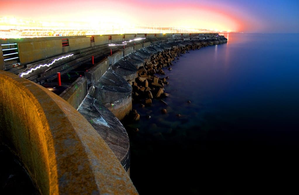 A breakwater running out into open water under a pale sky